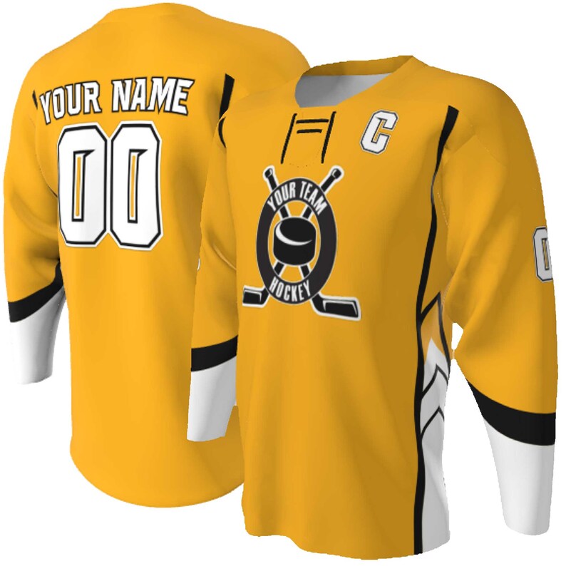 Puede incluir: Una camiseta de hockey amarilla con detalles en blanco y negro. El frente muestra un logotipo circular con un disco y palos cruzados, adem&aacute;s del texto YOUR TEAM HOCKEY y una letra C. La parte posterior muestra el texto YOUR NAME y el n&uacute;mero 00.