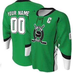 Puede incluir: Una camiseta de hockey verde brillante con cuello negro, pu&ntilde;os blancos y paneles laterales negros. El frente muestra un logo circular con un disco y palos cruzados, el texto YOUR TEAM HOCKEY y una letra C. La parte posterior muestra YOUR NAME y 00.