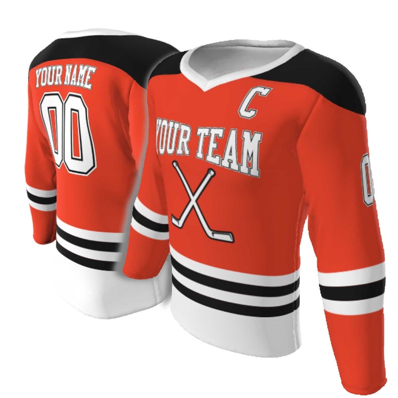 May include: An orange hockey jersey with black shoulders and white trim. The front features the text YOUR TEAM, a letter C, and crossed hockey sticks. The back displays YOUR NAME and the number 00. The sleeves have black and white stripes.