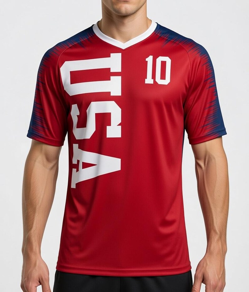 May include: Red athletic jersey with the word "USA" in large white letters and the number "10". The jersey has a white V-neck collar and navy blue accents on the shoulders and sleeves. The jersey is made of a breathable, athletic material.