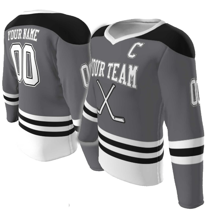 May include: A grey hockey jersey with black shoulder panels and white trim. The front features the text YOUR TEAM, a letter C, and crossed hockey sticks. The back displays YOUR NAME and the number 00. Sleeves show the number 00 and black stripes.