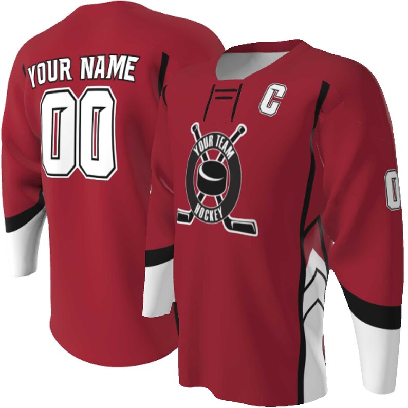 Puede incluir: Una camiseta de hockey roja con detalles en blanco y negro, un logotipo circular con un disco y palos, el texto YOUR TEAM HOCKEY, una letra C en el pecho y en la parte posterior el texto YOUR NAME con el n&uacute;mero 00 en color blanco.