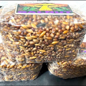 May include: Three rectangular blocks of compressed brown grains packaged in clear plastic wrap. Each block features a rectangular label on top with a yellow mushroom illustration and the text GALNUT in purple capital letters.