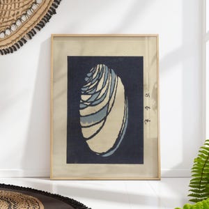 Pode incluir: Uma impressão emoldurada de uma concha azul e branca sobre um fundo azul escuro. A impressão tem texto japonês no canto inferior direito.