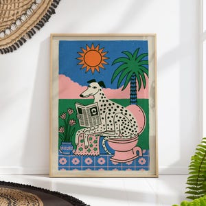 Può includere: Una stampa artistica incorniciata raffigurante un cane bianco a macchie nere seduto su un water rosa mentre legge un giornale. La scena include un sole arancione brillante, una palma verde, nuvole rosa e un pavimento piastrellato blu con fiori.
