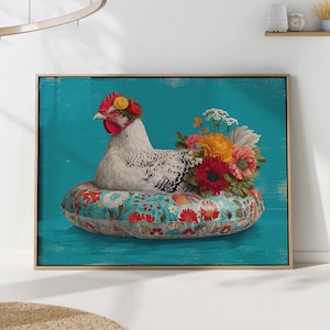 May include: Framed art print of a white chicken with black markings, wearing a floral crown, resting on a floral cushion. A bouquet of colourful flowers sits behind the chicken against a teal background.