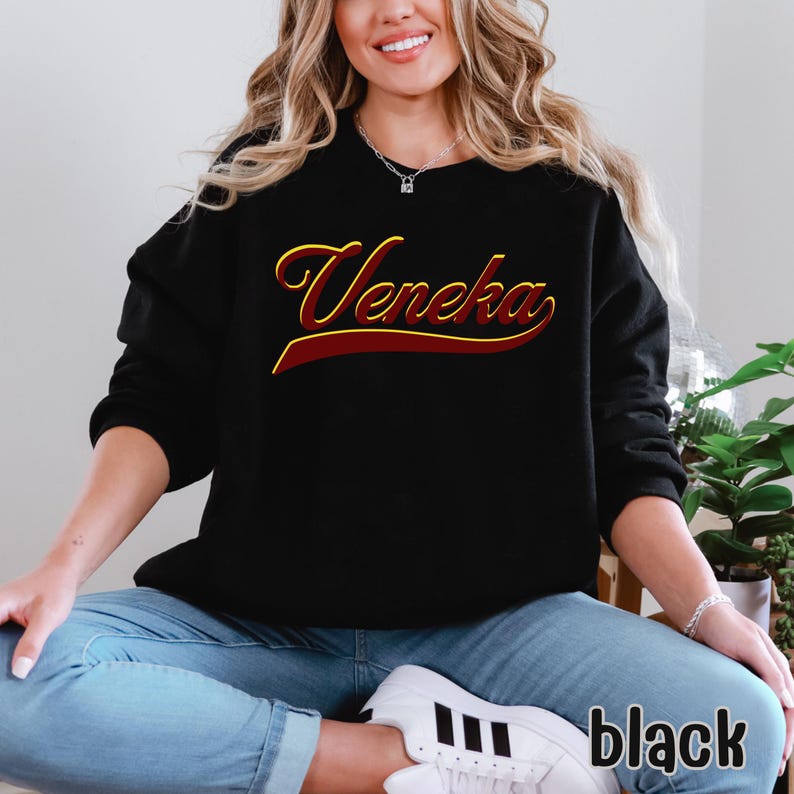 A person wearing a black crewneck sweatshirt with "Veneka" in red and yellow script across the chest, with "black" written in white in the bottom right corner.