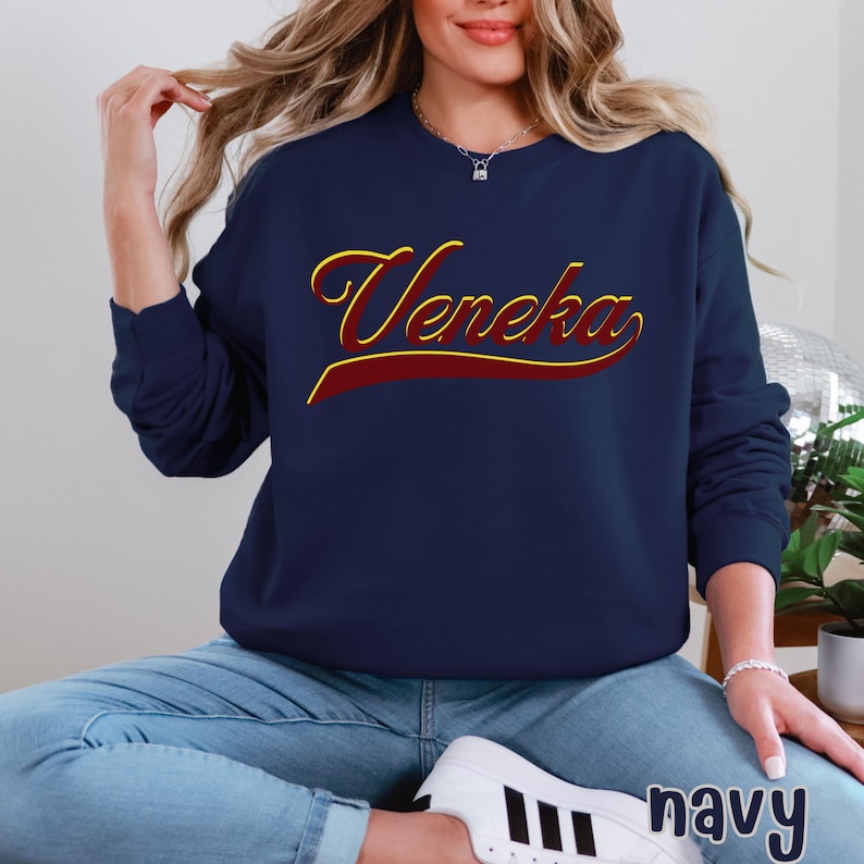 A person wearing a navy blue crewneck sweatshirt with "Veneka" in red and yellow script across the chest, with "navy" written in white in the bottom right corner.