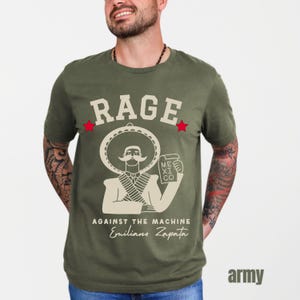May include: A green t-shirt with a white graphic of a man wearing a sombrero and holding a bottle of beer. The text "RAGE AGAINST THE MACHINE" and "Emiliano Zapata" is printed on the shirt.