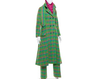 May include: A green, pink, and blue plaid coat, scarf, and pants set displayed on a mannequin. The long coat has a double-breasted design and pockets. The scarf is a solid pink color. The pants are straight-legged.