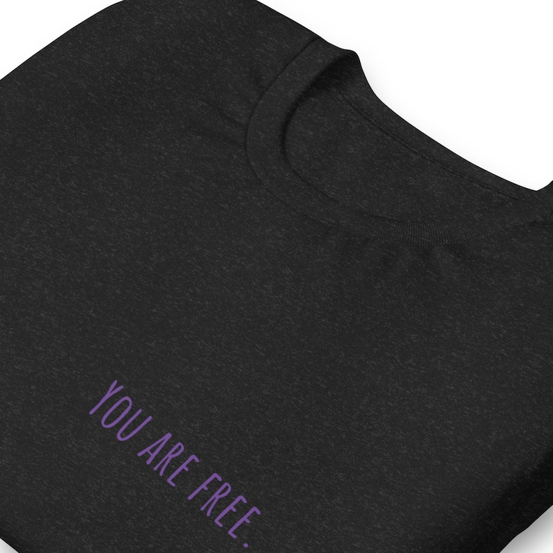May include: A black t-shirt with the text "YOU ARE FREE" printed in purple on the front.