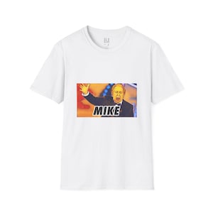 Può includere: T-shirt bianca con una grafica colorata di un uomo e la parola "MIKE" in grassetto. La grafica è centrata sulla parte anteriore della maglietta. La maglietta ha un girocollo e maniche corte.