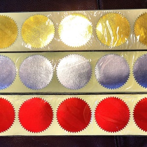 Sheets of blank circular serrated gold, silver, and red stickers.