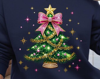 May include: Navy blue sweatshirt featuring a Christmas tree design. The tree is decorated with a pink bow, gold star, and gold garland. Pink and gold star accents surround the tree. The sweatshirt is a long-sleeved crew neck.