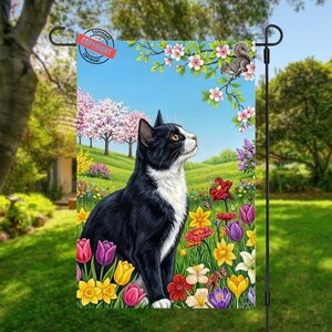 May include: A garden flag featuring a black and white cat gazing upwards in a vibrant flower garden. The scene includes colorful tulips, daffodils, and other flowers, with a blue sky and a squirrel in a tree.