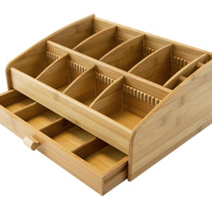 May include: A wooden organizer with multiple compartments and a drawer. The organizer is made of light brown bamboo and has a curved front edge.