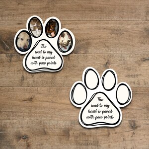 May include: Two paw print shaped stickers with black outlines and white interiors. Each sticker has a photo of a pet in the paw print and text that reads "The road to my heart is paved with paw prints".