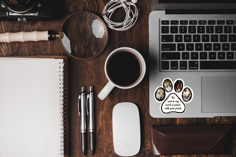 May include: A laptop computer with a paw print sticker that says "The road to my heart is paved with paw prints". The sticker has photos of dogs in each paw print.