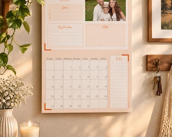Könnte beinhalten: Ein Wandkalender für Januar 2027 mit Spiralbindung und Aufhängeschlaufe. Das Design enthält ein Familienfoto, Bereiche für Ziele, Prioritäten, Notizen und eine Aufgabenliste sowie ein Kalendergitter für die Tage des Monats.