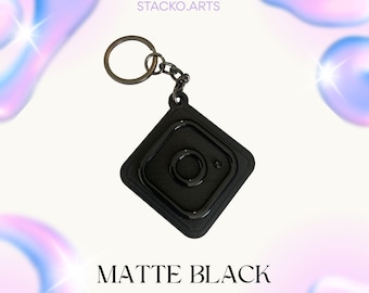 May include: Matte black keychain with a diamond-shaped design, a circular centre, and a metal keyring. The text "MATTE BLACK" and "www.instagram.com/stacko.arts" are visible.