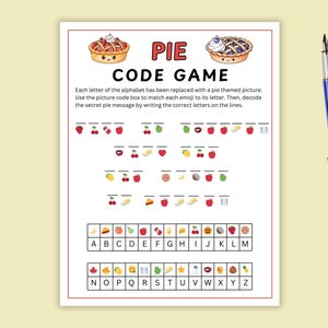 Puede incluir: Una hoja de trabajo imprimible "Pie Code Game" con un borde rojo. El juego presenta emojis con temática de pastel que representan letras del alfabeto. El texto "PIE CODE GAME" está en la parte superior. Un bolígrafo azul descansa sobre un fondo amarillo.