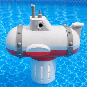 May include: A white and red submarine-shaped pool chemical dispenser floating in blue water. The toy-like vessel features gray bands with circular studs, a periscope, a small chimney, and a cylindrical white base with vertical slots for water flow.