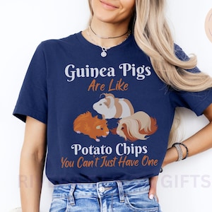 May include: A navy blue t-shirt with a graphic of three guinea pigs and the text "Guinea Pigs Are Like Potato Chips You Can't Just Have One".