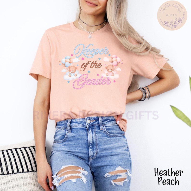 May include: A pink t-shirt with the text "Keeper of the Gender" in pink and blue lettering. Two teddy bears are holding balloons, one blue and one pink, and are floating on clouds with stars.