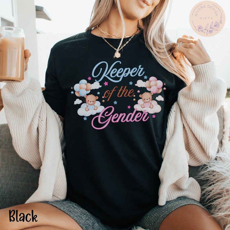 May include: Black t-shirt with the text "Keeper of the Gender" in pink and blue lettering. The design features two teddy bears with blue and pink balloons, surrounded by clouds and stars.