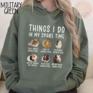 Pu&ograve; includere: Una felpa con cappuccio verde con il testo "Things I do in my spare time" e un elenco di attivit&agrave; legate ai porcellini d'India. Le attivit&agrave; includono "Parlare di porcellini d'India", "Guardare i porcellini d'India", "Ricercare i porcellini d'India", "Guardare video di porcellini d'India", "Giocare con i porcellini d'India" e "Sognare i porcellini d'India". Ogni attivit&agrave; &egrave; illustrata con una foto di un porcellino d'India.