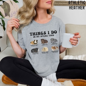 May include: A gray t-shirt with the text "Things I do in my spare time" and illustrations of guinea pigs. The text below the illustrations includes phrases like "Hang out with guinea pigs", "Look at guinea pigs", "Research guinea pigs", "Talk about guinea pigs", "Dream about guinea pigs", and "Watch guinea pig videos".