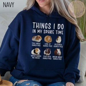 Pu&ograve; includere: Una felpa con cappuccio blu navy con il testo "Things I do in my spare time" e una serie di immagini di porcellini d'India con didascalie che descrivono attivit&agrave; legate ai porcellini d'India.