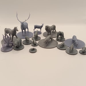 May include: A collection of gray plastic animal figurines, including a deer, a lion, a bear, a horse, and several smaller animals. The figurines are arranged on small round bases.