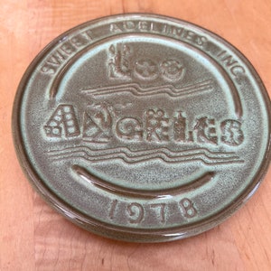 May include: A green ceramic coaster with the text "Sweet Adelines Inc." and "Lee Acres" in a stylised font. The year "1978" is also printed on the coaster.
