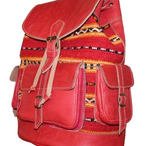 Puede incluir: Mochila de cuero roja con dos bolsillos delanteros y cierre de solapa. La mochila presenta un panel de tela tejida colorida con rayas rojas, amarillas, negras y blancas. La bolsa tiene correas ajustables y cierre de hebilla.