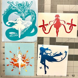 Puede incluir: Cuatro pegatinas de vinilo con siluetas de estilo anime. Una muestra un drag&oacute;n verde azulado con una figura blanca, otra una figura roja con cintas, una blanca entre llamas naranjas y una azul oscuro rodeada de peque&ntilde;as mariposas.