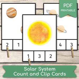 May include: Educational printable cards with illustrations of planets and the sun. Each card has a number and a corresponding image of a planet or the sun. The cards are designed for counting and clipping activities. The text "Solar System Count and Clip Cards" is visible.