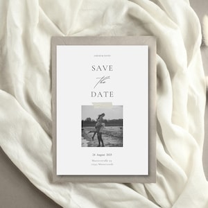 May include: A minimalist wedding invitation with the text "SAVE THE DATE" in elegant script. The invitation features a black and white photo of a couple and is set against a neutral background.