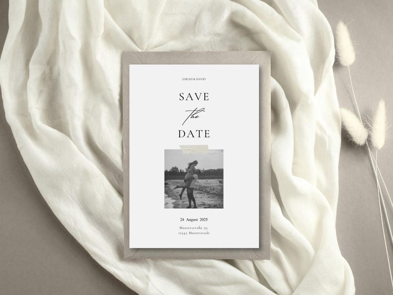 May include: A minimalist wedding invitation with the text "SAVE THE DATE" in elegant script. The invitation features a black and white photo of a couple and is set against a neutral background.