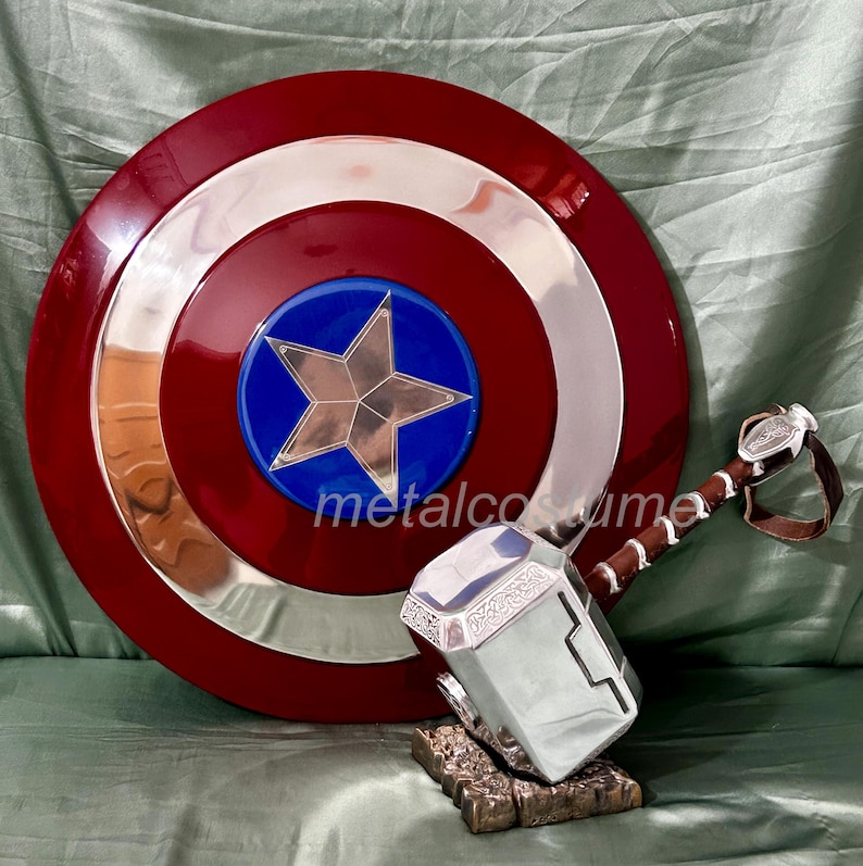 Op de afbeelding: Een rood, wit en blauw Captain America-schild met een zilveren ster in het midden, en een zilveren Thor-hamer met een bruine leren handgreep.