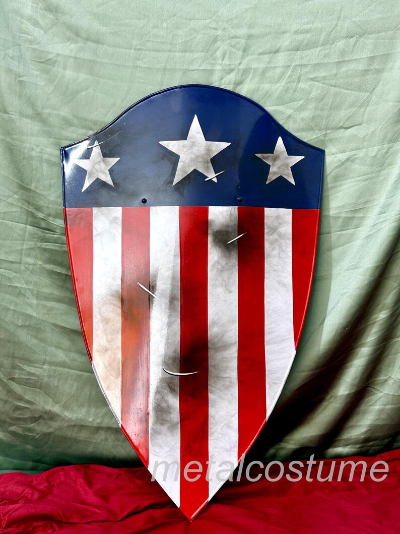 Puede incluir: Un escudo rojo, blanco y azul con un aspecto desgastado. El escudo tiene cinco estrellas blancas sobre un fondo azul y rayas rojas y blancas.
