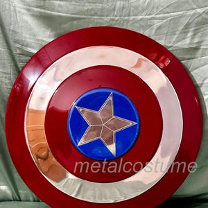 Op de afbeelding: Een rood, wit en blauw Captain America schild met een zilveren ster in het midden. Het schild is gemaakt van plastic en heeft een glanzende afwerking.