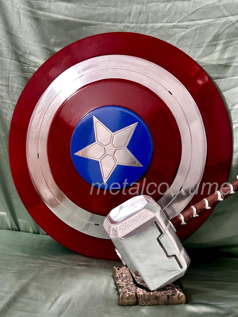 Op de afbeelding: Een rood, wit en blauw Captain America schild met een zilveren ster in het midden, en een zilveren Thor's hamer met een bruine handvat.