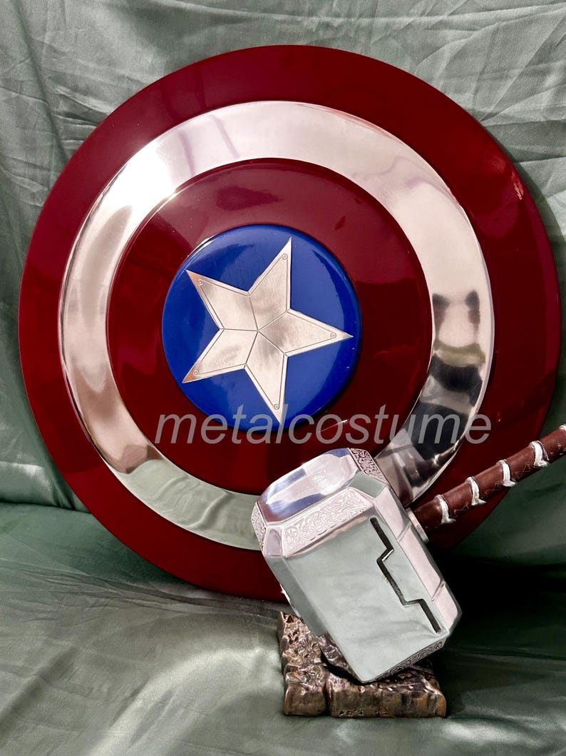Op de afbeelding: Een rood, wit en blauw Captain America schild met een zilveren ster in het midden, en een zilveren Thor's hamer met een bruine handvat.