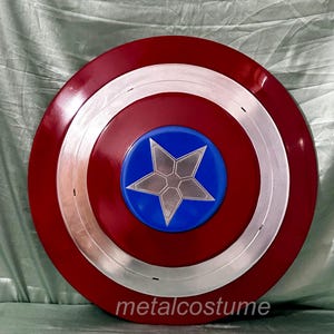 Op de afbeelding: Een rood, wit en blauw Captain America schild met een zilveren ster in het midden. Het schild is gemaakt van metaal en heeft een glanzende afwerking.
