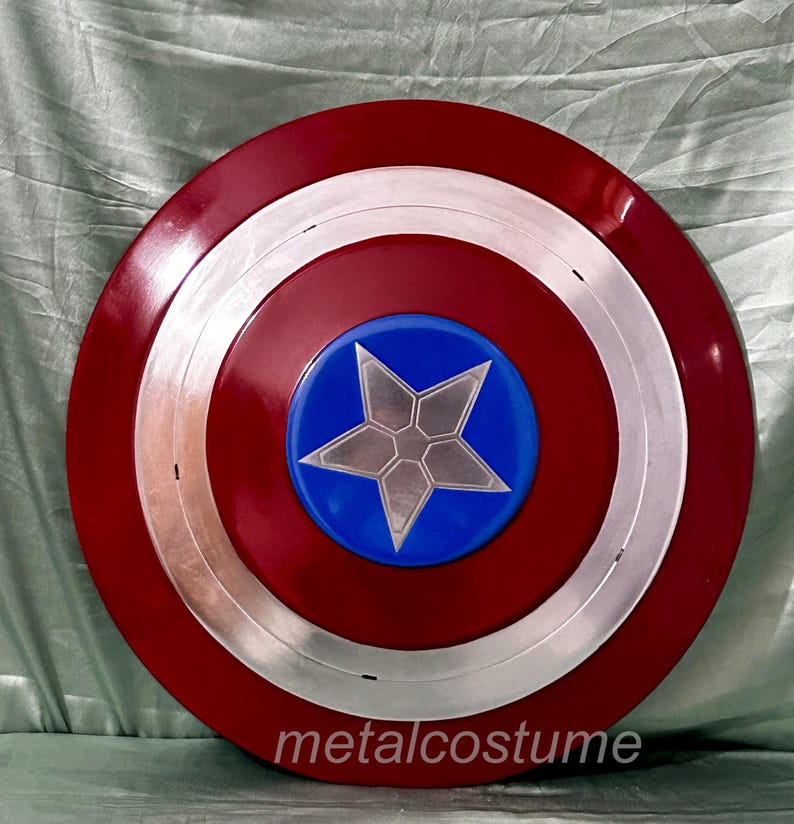 Op de afbeelding: Een rood, wit en blauw Captain America schild met een zilveren ster in het midden. Het schild is gemaakt van metaal en heeft een glanzende afwerking.