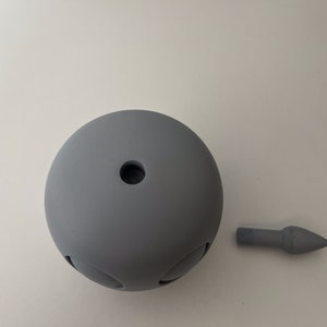 May include: A gray, round, ceramic object with a small hole in the center. A gray, pointed, ceramic object is also shown.