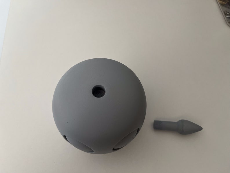 May include: A gray, round, ceramic object with a small hole in the center. A gray, pointed, ceramic object is also shown.