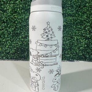May include: White Owala water bottle with a gray lid and handle. The bottle features a black line drawing of Snoopy, a Christmas tree, and snowflakes. The word "owala" is printed on the bottle.