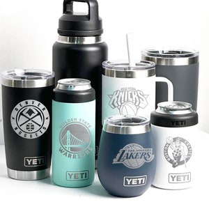 Puede incluir: Una colección de recipientes aislados para bebidas con logotipos de equipos deportivos. Incluye una botella de agua negra, vasos y enfriadores de latas. Logotipos: Denver Nuggets, Golden State Warriors, New York Knicks, Los Angeles Lakers y Boston Celtics.